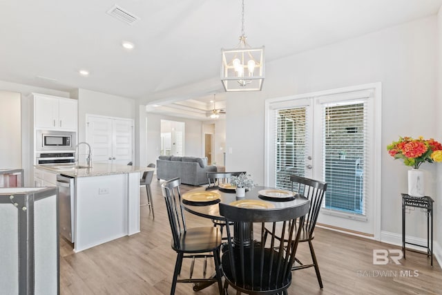 dining room featuring an inviting chandelier, light wood-type flooring, sink, and french doors