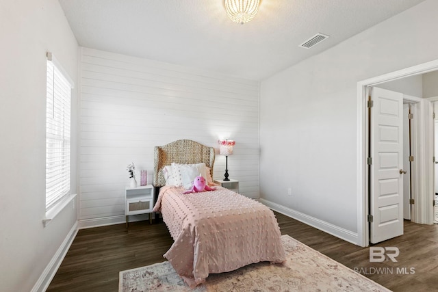 bedroom featuring a textured ceiling, multiple windows, and dark wood-type flooring