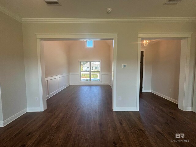 spare room featuring crown molding, dark wood-type flooring, and a notable chandelier