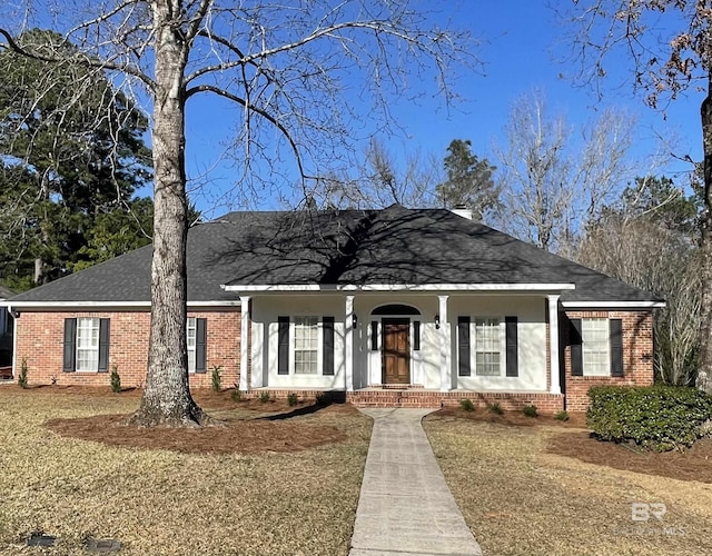 view of front of house featuring brick siding and roof with shingles