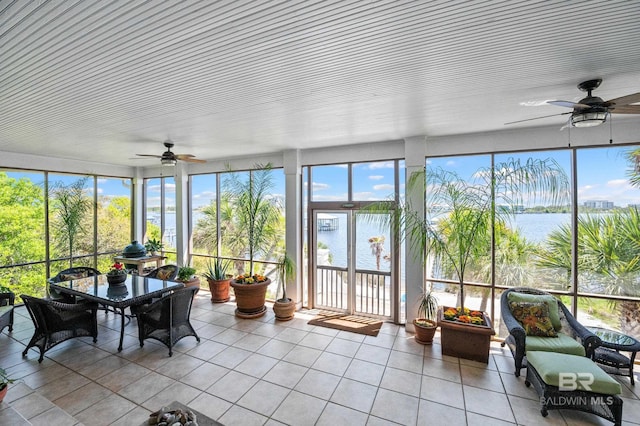 sunroom / solarium featuring a wealth of natural light, tile patterned floors, and a water view