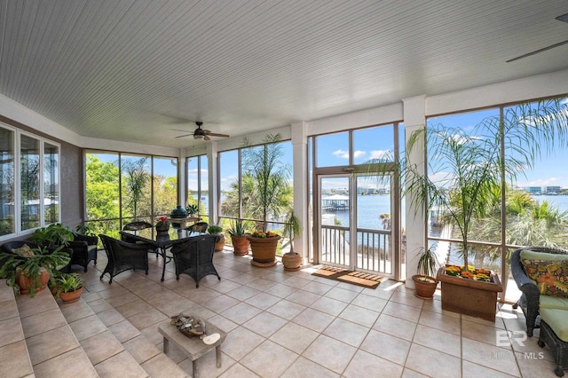 sunroom / solarium with tile patterned flooring, a water view, and a healthy amount of sunlight