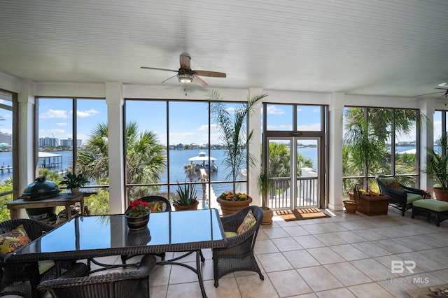 sunroom / solarium with a healthy amount of sunlight, tile patterned floors, and a water view