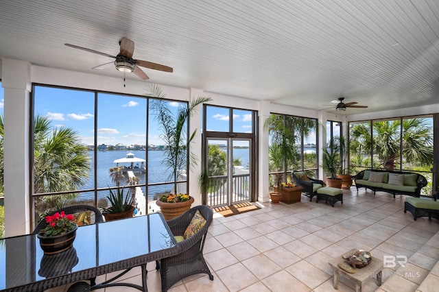 sunroom / solarium featuring an outdoor living space, a ceiling fan, tile patterned floors, and a water view