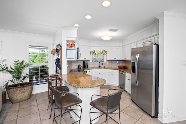 kitchen with a breakfast bar, a sink, light tile patterned flooring, a peninsula, and appliances with stainless steel finishes