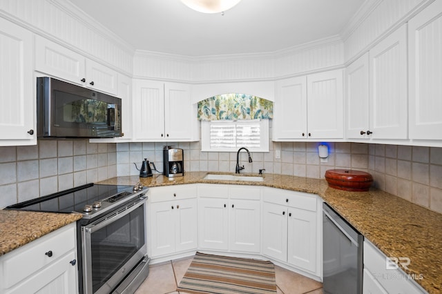 kitchen with a sink, stainless steel appliances, backsplash, white cabinetry, and light stone countertops