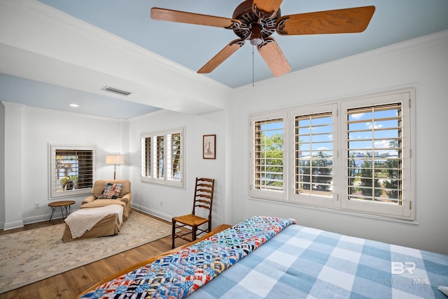 bedroom with wood finished floors, visible vents, crown molding, and multiple windows