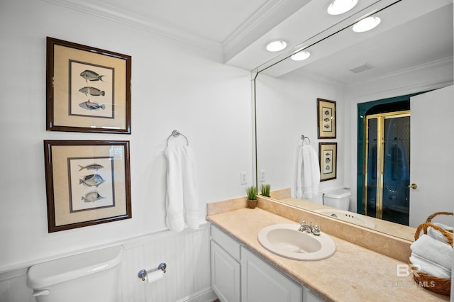 full bath with toilet, vanity, ornamental molding, wainscoting, and a stall shower