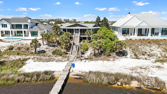 rear view of house featuring stairway, a chimney, a sunroom, and a water view