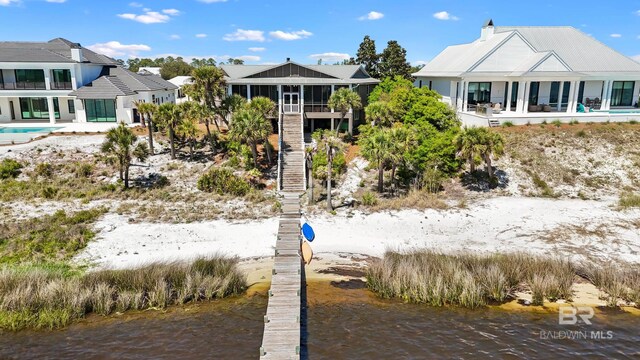 rear view of house with a sunroom, a water view, and stairs