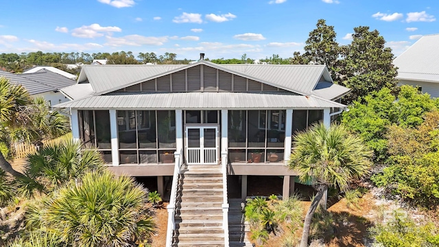 back of property with stairway, a sunroom, and metal roof