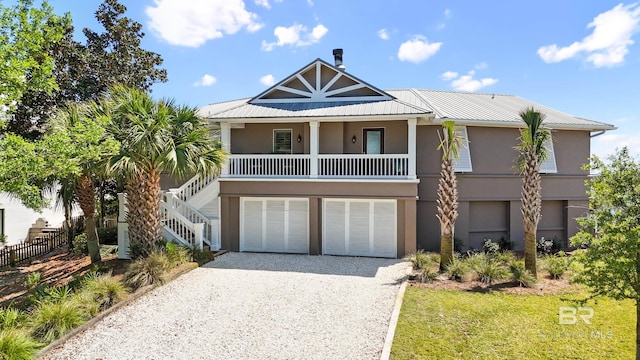 coastal home featuring driveway, metal roof, fence, an attached garage, and stairs
