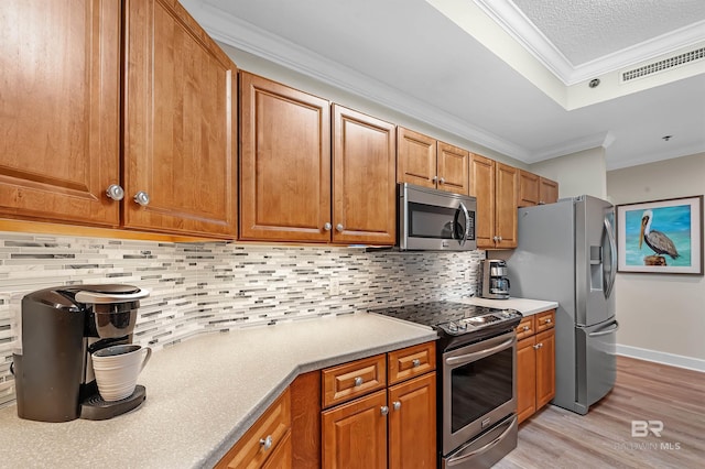 kitchen featuring decorative backsplash, stainless steel appliances, light wood-type flooring, crown molding, and a textured ceiling