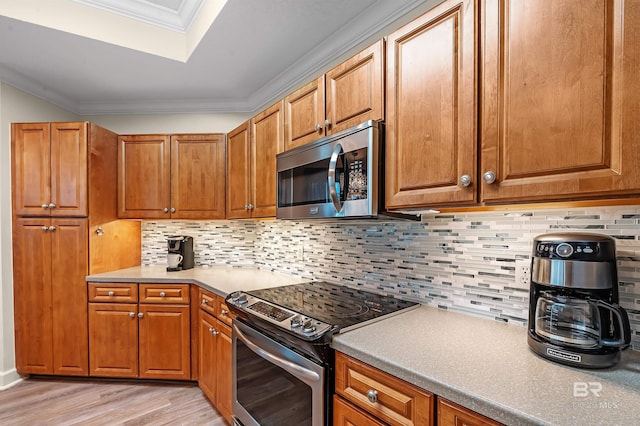 kitchen featuring appliances with stainless steel finishes, crown molding, light hardwood / wood-style flooring, and tasteful backsplash