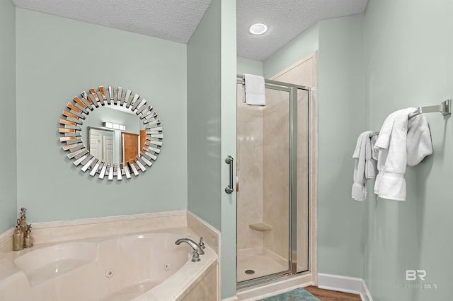 bathroom with a textured ceiling, independent shower and bath, and hardwood / wood-style floors