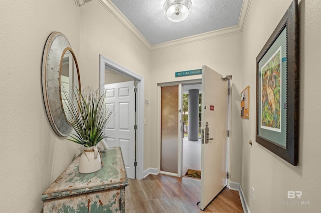 corridor with light wood-type flooring, a textured ceiling, and ornamental molding