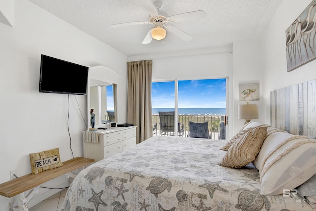 bedroom featuring ceiling fan, access to exterior, and a textured ceiling