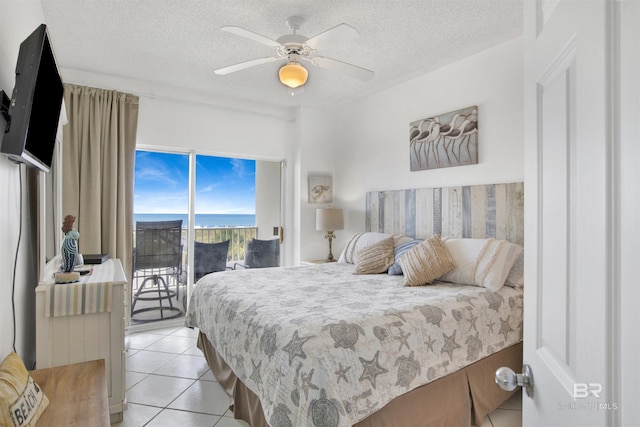 tiled bedroom featuring access to exterior, ceiling fan, a textured ceiling, and a water view