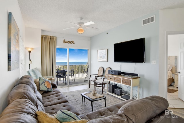 living room featuring ceiling fan, a textured ceiling, and light wood-type flooring