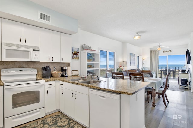 kitchen with sink, white appliances, kitchen peninsula, and white cabinets