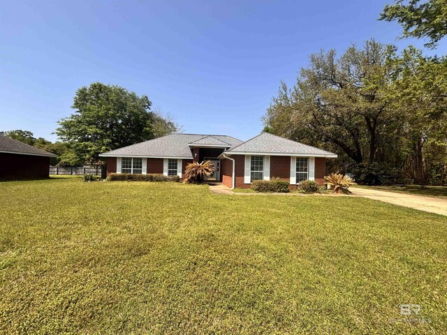 single story home featuring concrete driveway, a front yard, and brick siding