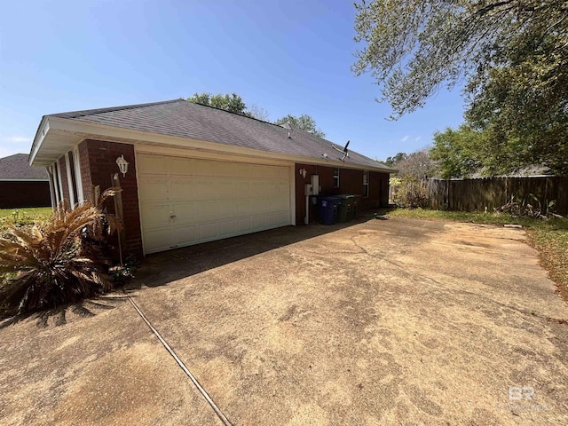 view of home's exterior with concrete driveway, a shingled roof, a garage, and fence
