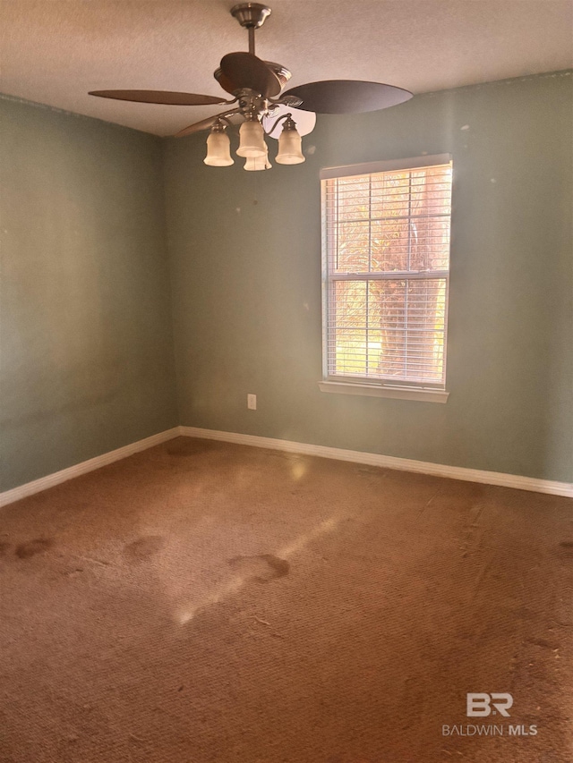 carpeted empty room with a textured ceiling, ceiling fan, and baseboards