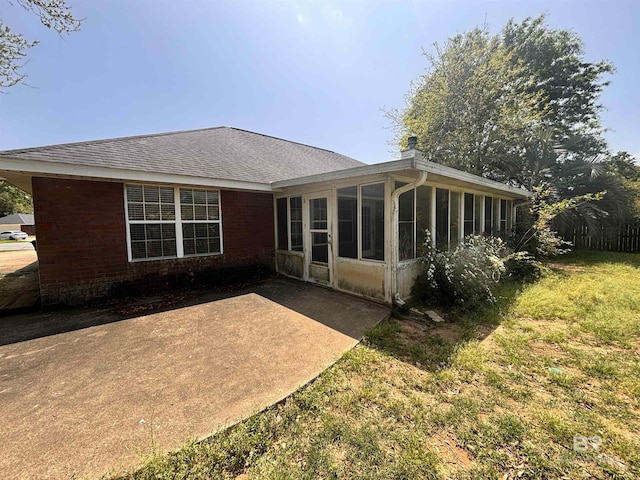 back of house with a sunroom, roof with shingles, and a patio