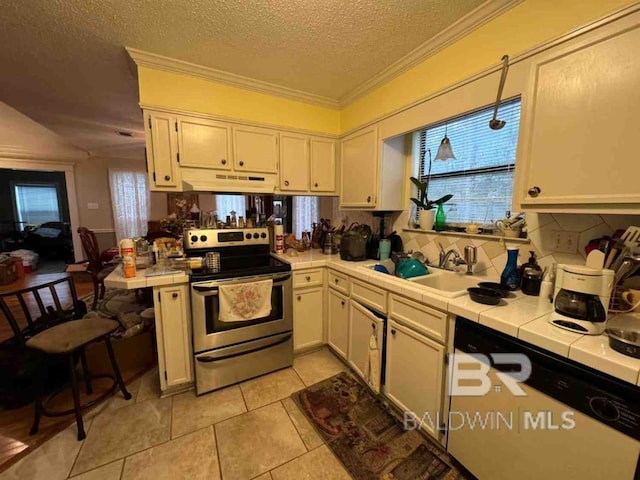 kitchen featuring a wealth of natural light, tile counters, stainless steel range with electric stovetop, and sink