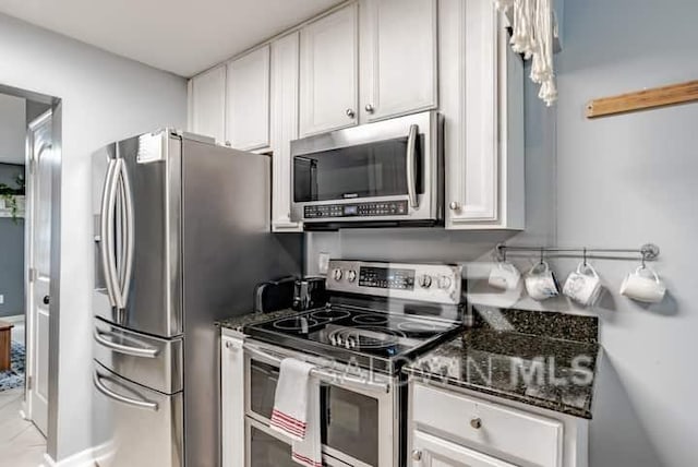 kitchen featuring appliances with stainless steel finishes, dark stone counters, and white cabinets