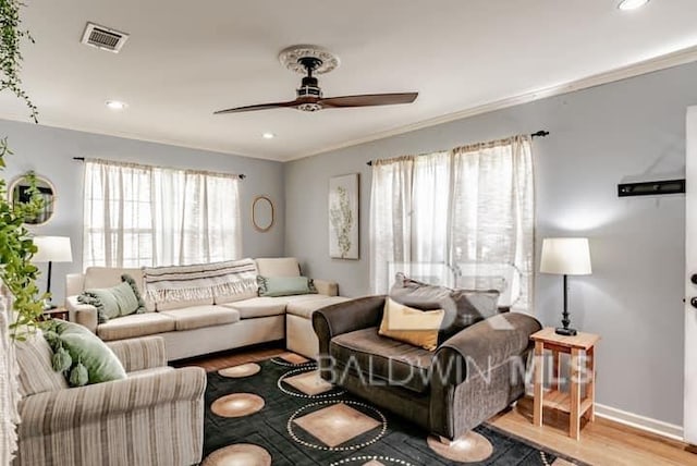 living room with ornamental molding, ceiling fan, and light hardwood / wood-style flooring