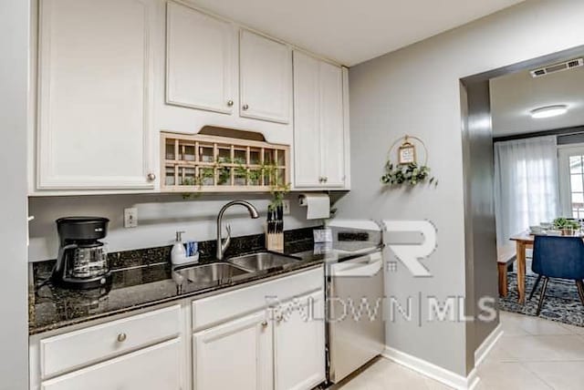 kitchen featuring dark stone counters, sink, and white cabinets