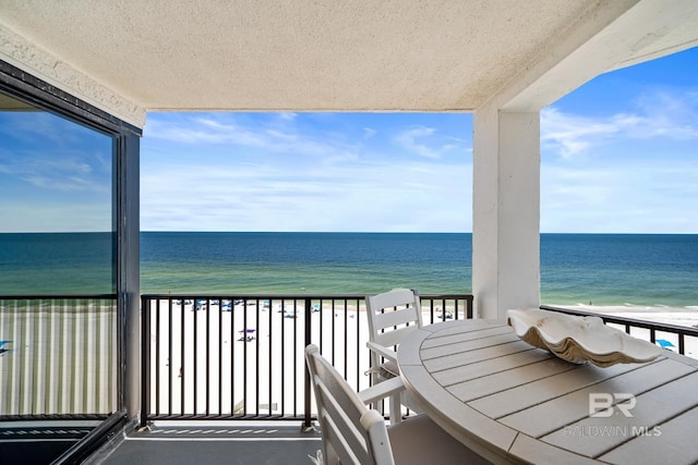 balcony with a water view and a view of the beach