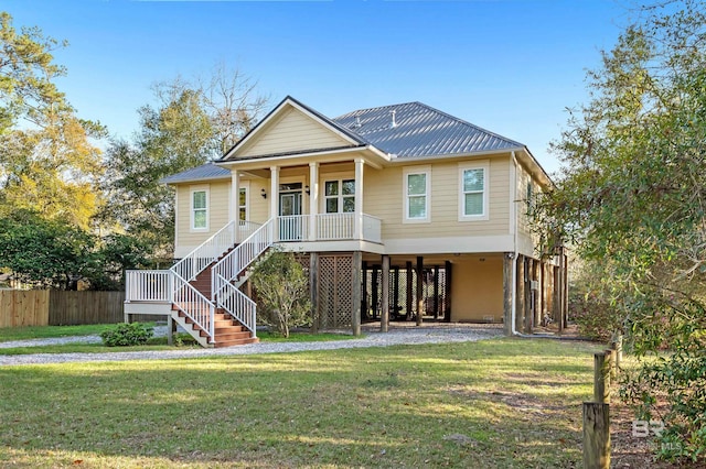 raised beach house featuring a front yard, stairway, a porch, a carport, and metal roof