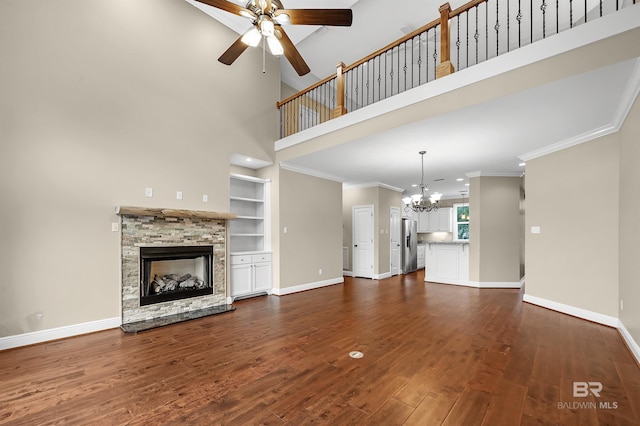 unfurnished living room featuring crown molding, baseboards, built in features, a fireplace, and dark wood-style flooring