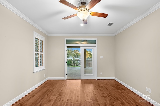 unfurnished room with crown molding, wood finished floors, baseboards, and visible vents