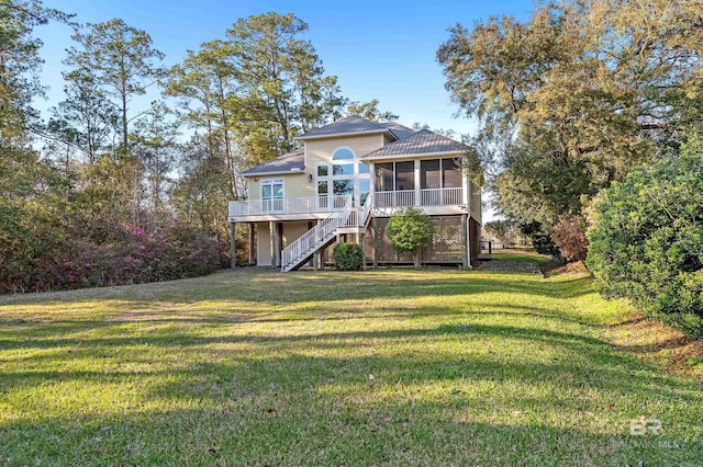 rear view of house featuring metal roof, a lawn, stairs, and a sunroom