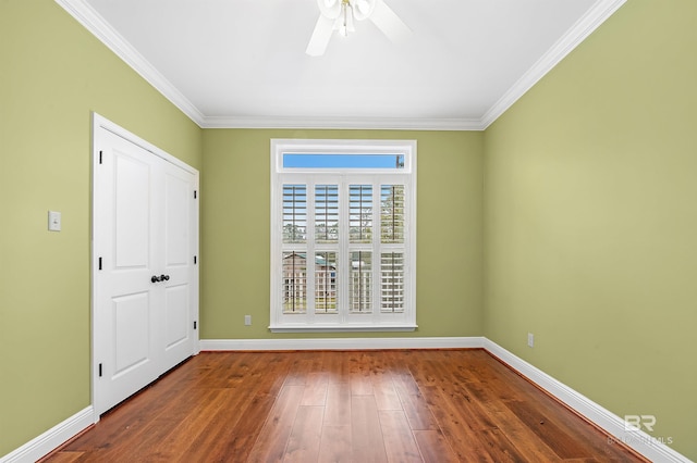 unfurnished room featuring crown molding, baseboards, and wood finished floors