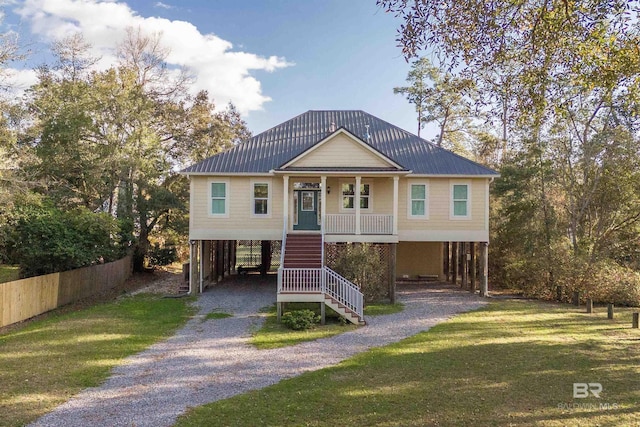 coastal inspired home with gravel driveway, stairs, covered porch, metal roof, and a carport