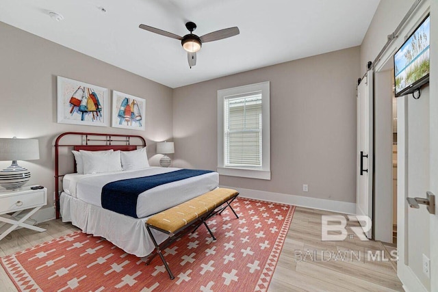951 W Lagoon Ave, Gulf Shores, AL 36542 - bedroom with multiple windows, wood finished floors, a barn door, and ceiling fan