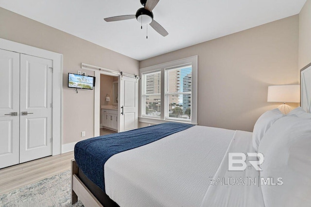 951 W Lagoon Ave, Gulf Shores, AL 36542 - bedroom with a barn door, light wood-style floors, ceiling fan, and ensuite bathroom