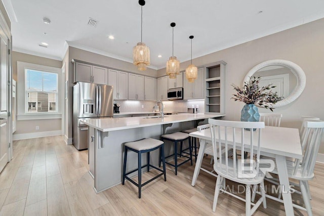 951 W Lagoon Ave, Gulf Shores, AL 36542 - kitchen with appliances with stainless steel finishes, open shelves, ornamental molding, a breakfast bar area, and tasteful backsplash