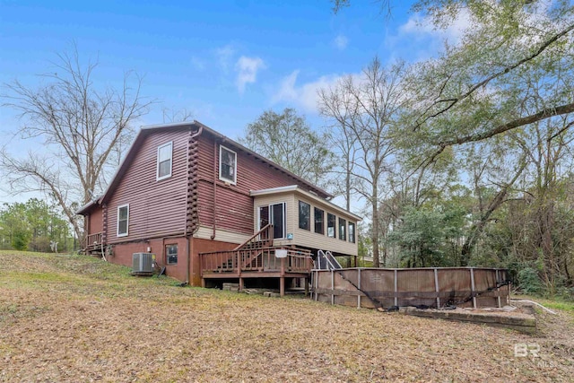 rear view of property featuring a wooden deck, a sunroom, a yard, and central air condition unit