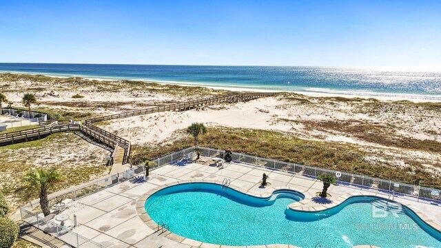 view of swimming pool featuring a view of the beach, a patio, and a water view