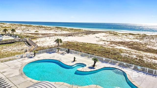 view of pool with a patio, a water view, and a beach view