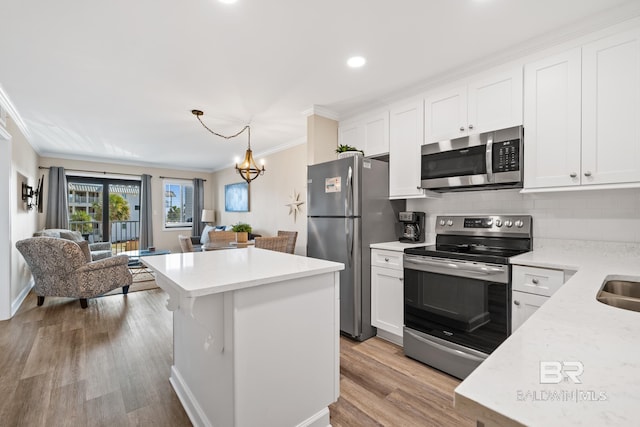 kitchen with white cabinetry, hanging light fixtures, stainless steel appliances, crown molding, and light hardwood / wood-style flooring