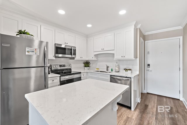 kitchen with sink, stainless steel appliances, a center island, light stone counters, and white cabinets