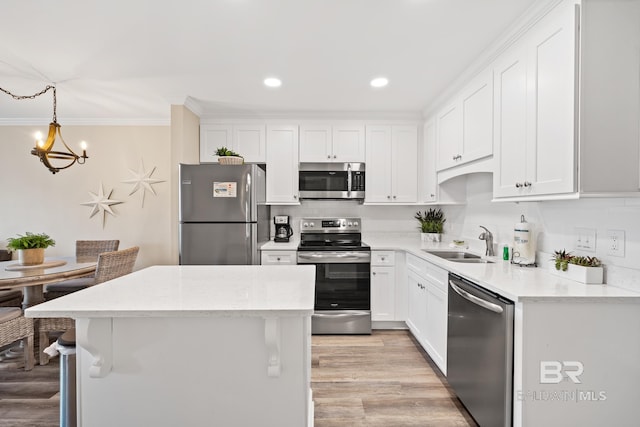 kitchen featuring sink, white cabinetry, stainless steel appliances, ornamental molding, and decorative light fixtures