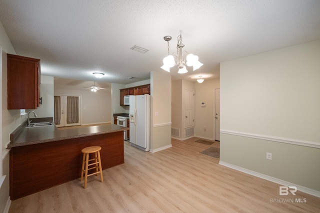 kitchen featuring sink, hanging light fixtures, light hardwood / wood-style flooring, kitchen peninsula, and white appliances