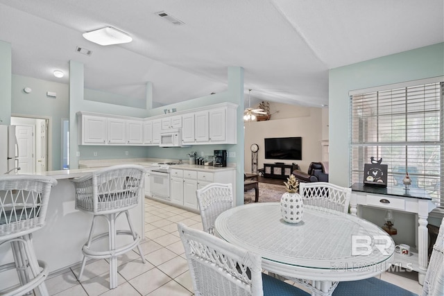 dining area with vaulted ceiling, light tile patterned flooring, a ceiling fan, and visible vents